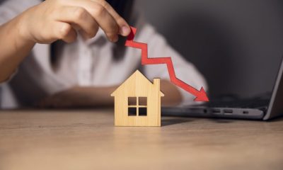 woman-hand-holding-house-model-with-red-arrow-down-down-1024x683-1